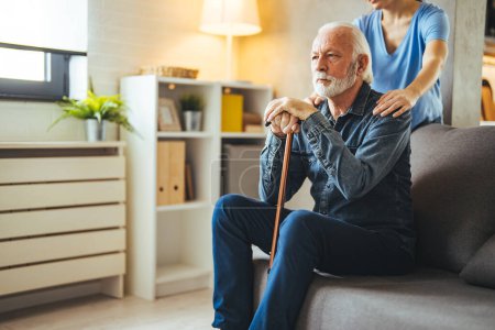 Photo for Cropped nurse holding hands on shoulders of thinking senior man with disabled stick on sofa at home - Royalty Free Image