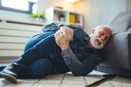 Photo for Senior caucasian man lying on on floor and suffering from pain near sofa at home - Royalty Free Image
