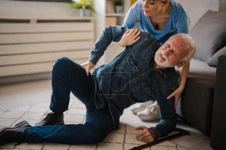 Photo for Obscure face of nurse helping senior man standing up from floor at home - Royalty Free Image