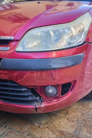 Close-up of a scratched bumper of a red car. Car crash or accident. Broken vehicle detail. Parking issues concept.