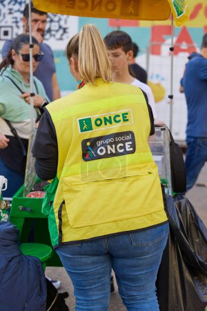 Photo for View of back of the dressing of a woman selling lottery tickets for helping blind people with the logo of 'Once' organization. Valencia, Spain - March 16, 2024. - Royalty Free Image