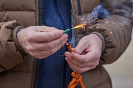 Close up of man hand lighting up a firecrackers with wick. Man holding a burning petard in his hand.
