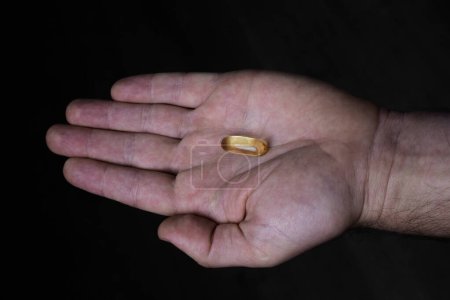 Omega 3 gold fish oil capsule on the male hand.