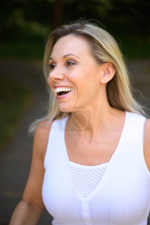 Photo for Cute vivacious blond middle aged woman outdoors laughing happily as she looks to the side - Royalty Free Image
