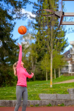 Foto de Atractiva mujer rubia lanzando cestas mientras juega baloncesto en un campo deportivo - Imagen libre de derechos