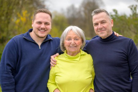 Photo for Three generation family, grandmother, son and grandson hold each other and smile happily at the camera - Royalty Free Image