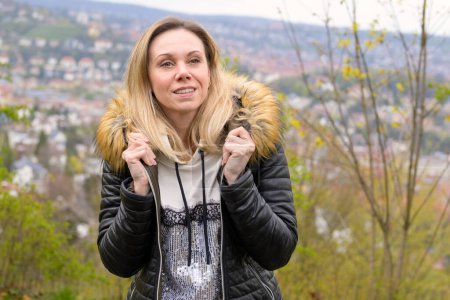 Téléchargez les photos : Portrait d'une jolie femme blonde dans la quarantaine portant une tenue en cuir avec les deux mains à la mode sur sa veste sur une montagne près de Stuttgart en Allemagne - en image libre de droit