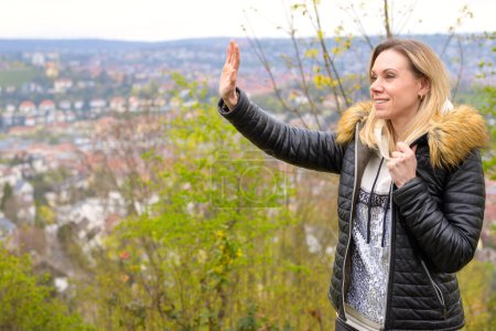 Téléchargez les photos : Jolie femme blonde dans la quarantaine portant une tenue en cuir agitant vers quelqu'un sur une montagne près de Stuttgart en Allemagne - en image libre de droit