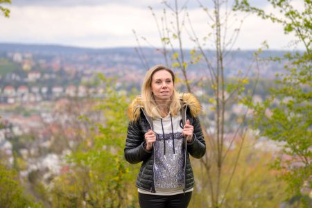 Foto de Atractiva mujer rubia de unos cuarenta años con un atuendo de cuero con ambas manos a la moda en su chaqueta en una montaña cerca de Stuttgart en Alemania - Imagen libre de derechos