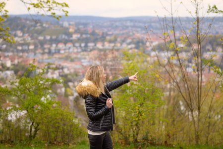 Téléchargez les photos : Superbe femme séduisante dans la quarantaine portant une tenue en cuir pointant vers l'arrière-plan sur une montagne près de Stuttgart en Allemagne - en image libre de droit