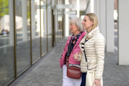 Téléchargez les photos : Mère et fille faisant du shopping dans un centre commercial et regardant sur le côté dans la vitrine - en image libre de droit