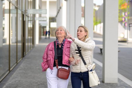 Téléchargez les photos : Mère et fille faisant du shopping dans un centre commercial et la fille pointe du doigt un magasin - en image libre de droit