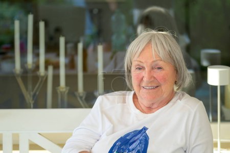 Foto de Retrato de una anciana sentada en la terraza y mirando pensativa a la cámara - Imagen libre de derechos