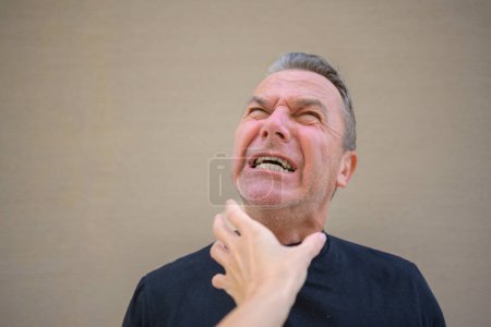 Foto de Hombre atractivo grita mientras la mano de un extraño está en su cuello - Imagen libre de derechos