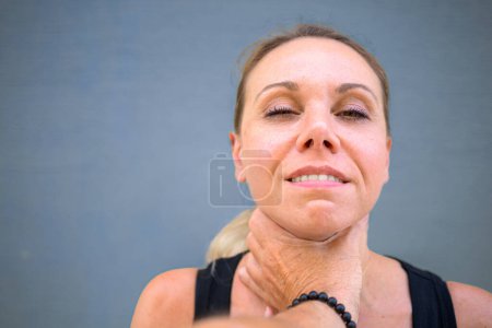 Photo for Pretty attractive woman with a mischievous smile is looking at the camera while a stranger's hand is on her neck with a blue background - Royalty Free Image