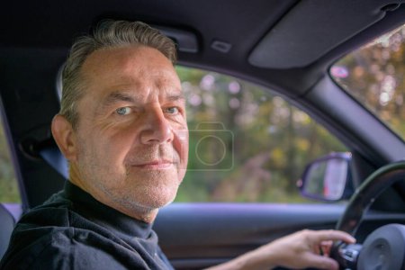 Téléchargez les photos : Homme d'âge moyen conduisant dans sa voiture et regardant à la caméra - en image libre de droit