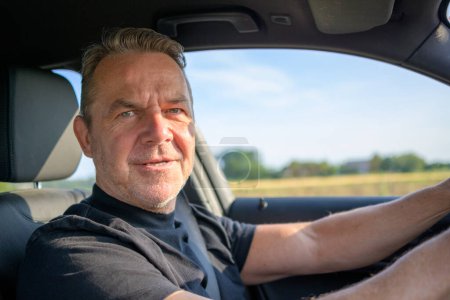 Foto de Hombre de mediana edad conduciendo en su coche y mirando a la cámara - Imagen libre de derechos