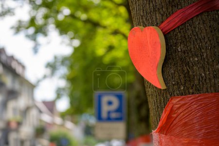 Téléchargez les photos : Gros plan d'un arbre dans la ville avec un cœur rouge et un ruban rouge comme signe pour sauver les arbres - en image libre de droit