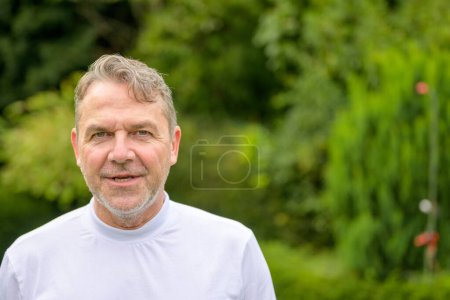 Foto de Retrato de un hombre serio y amargado de mediana edad mirando a la cámara mientras estaba de pie en el jardín - Imagen libre de derechos