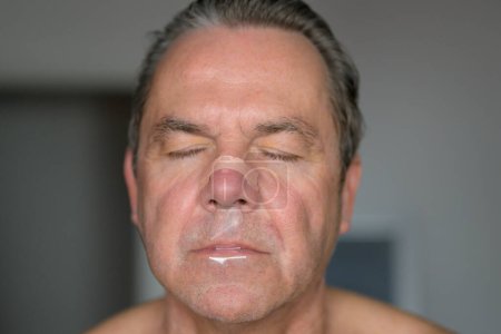 Close up of a middle aged man with a nose tape and a mouth tape standing in the bedroom