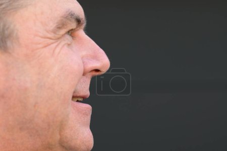Foto de Extremo retrato de vista lateral de un hombre de mediana edad con la boca abierta sin prótesis dental frente a una pared negra - Imagen libre de derechos