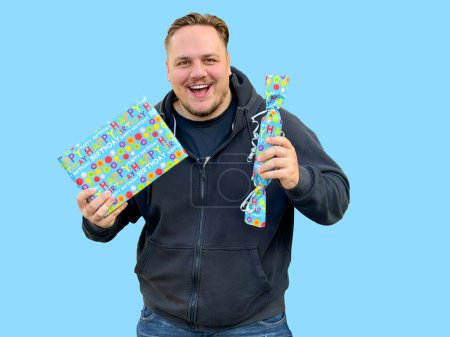 Foto de Primer plano de un joven feliz sosteniendo dos cajas azules con regalos y mirando a la cámara, en el estilo de candycore - Imagen libre de derechos