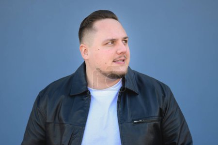 Photo for Young attractive man in his twenties in a black leather jacket looking in to the distance - Royalty Free Image
