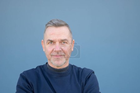 Close up portrait of a middle aged man looking doubtfully or scared at the camera with wide eyes wearing a blue sweater