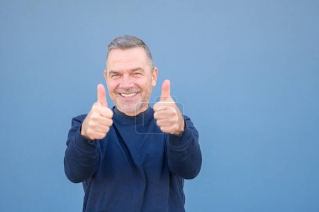 Foto de Primer plano de un hombre atractivo motivado entusiasta de mediana edad dando un gesto de aprobación y éxito con una sonrisa radiante - Imagen libre de derechos