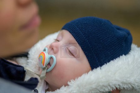Téléchargez les photos : Extrême gros plan de petit bébé dormant avec une sucette et un chapeau bleu en plein air - en image libre de droit