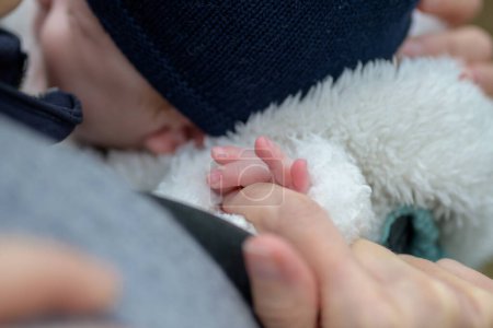 Téléchargez les photos : Gros plan de la main du petit bébé tenant la main des mères avec ses petits doigts en plein air - en image libre de droit