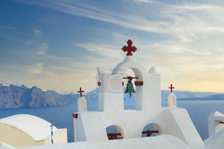 Photo for White bell tower with red cross on Santorini island, Greece. Beautiful landscape with caldera sea view and cloudy sky. Summer vacation destination. - Royalty Free Image