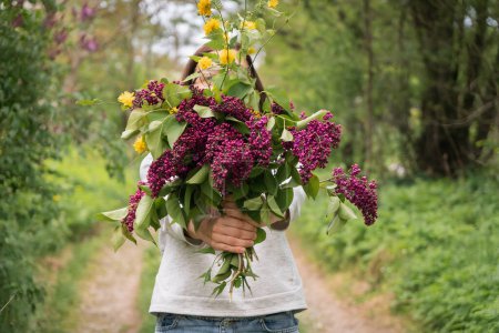 A woman holds a lilac flower bouquet.