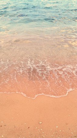 Serene beach scene with gentle waves meeting sandy shore. Blue clear water, orange sand. Copy space summer vacations ads background.