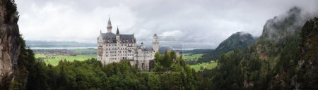Téléchargez les photos : Château de Neuschwanstein à Fussen, superbe palais néogothique du XIXe siècle et monument le plus célèbre de Bavière, Allemagne. Vue du pont Marienbrucke par une journée nuageuse et pluvieuse - en image libre de droit