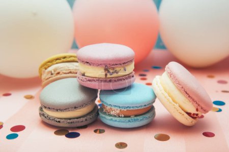 Foto de Pasteles de colores pastel macaron sobre fondo azul y rosa con globos de aire y decoración - Imagen libre de derechos