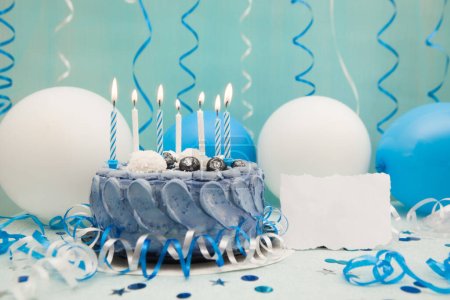 Photo for Blue birthday cake with candles and paper blank and celebration decoration - Royalty Free Image