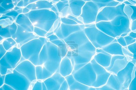 Agua azul clara en la piscina bajo los rayos del sol.