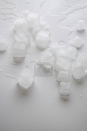 Téléchargez les photos : Ice cubes with water drops scattered on white background. Top view, flat lay. - en image libre de droit