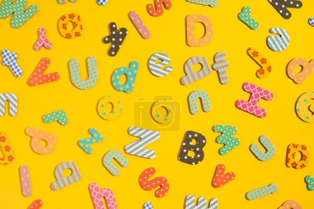 Téléchargez les photos : Beaucoup de lettres multicolores de l'alphabet sur un fond jaune. Vue de dessus, plan plat. - en image libre de droit