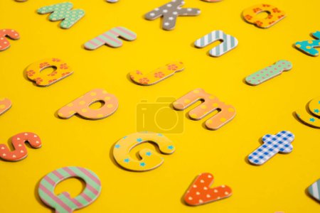 Téléchargez les photos : Nombreuses lettres multicolores de l'alphabet sur fond jaune. - en image libre de droit