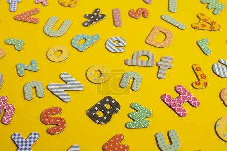 Téléchargez les photos : Beaucoup de lettres multicolores de l'alphabet sur un fond jaune. Vue de dessus, plan plat. - en image libre de droit