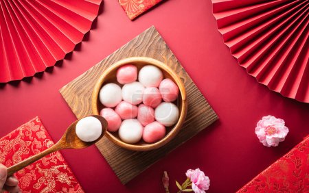 Tang Yuan (süße Knödelbällchen), eine traditionelle Küche für den Herbst, Dongzhi (Wintersonnenwende) und das chinesische Neujahr mit Pflaumenblüten und Tee auf rotem Hintergrund.