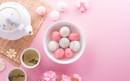 Photo for Tang Yuan(sweet dumplings balls), a traditional cuisine for Mid-autumn, Dongzhi (winter solstice ) and Chinese new year with plum flower and tea on pastel background. - Royalty Free Image