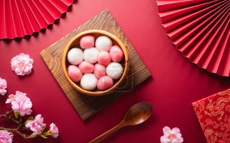 Photo for Tang Yuan(sweet dumplings balls), a traditional cuisine for Mid-autumn, Dongzhi (winter solstice ) and Chinese new year with plum flower and tea on red background. - Royalty Free Image