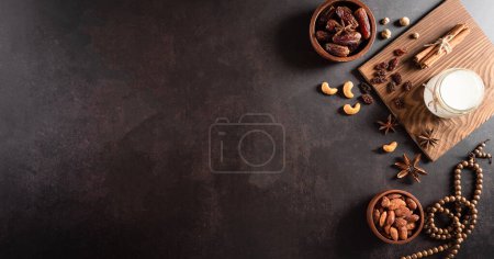Photo for Table top view image of decoration Ramadan Kareem, dates fruit, milk and almond on dark stone background. Flat lay with copy space. - Royalty Free Image