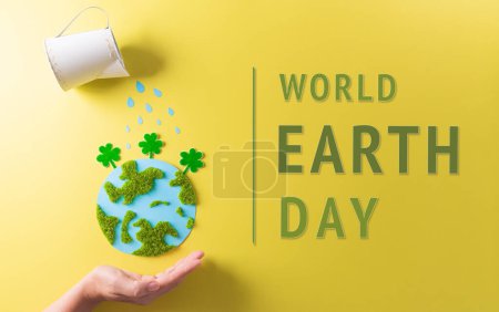 Hands holding paper earth with tree on yellow background. World environment day, earth day and save earth concept.
