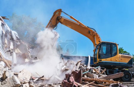 Foto de Demolition of building. Excavator destroy old house. - Imagen libre de derechos