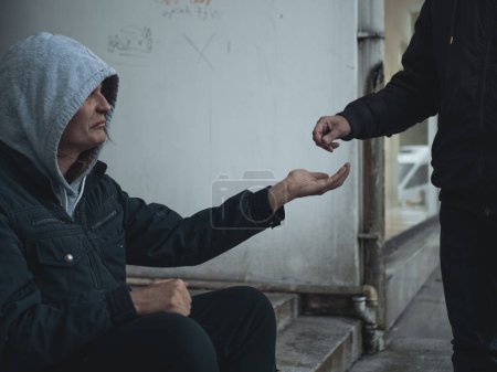 Photo for Homeless man sits on steps and asks for help and money. - Royalty Free Image
