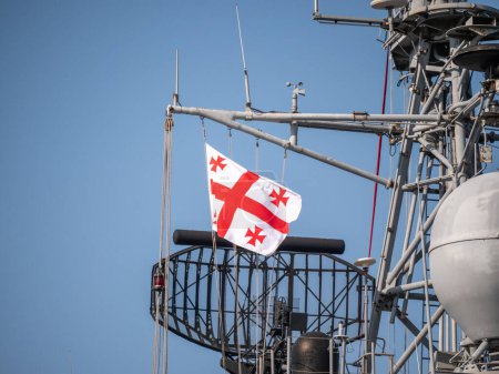 Georgische Flagge weht auf dem Radarturm des Marineschiffes, mit komplizierter Kommunikationsausrüstung vor blauem Himmel